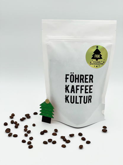 Beutel des Föhrer Winterkaffees 2025 neben einigen Kaffeebohnen und Weihnachtsdeko